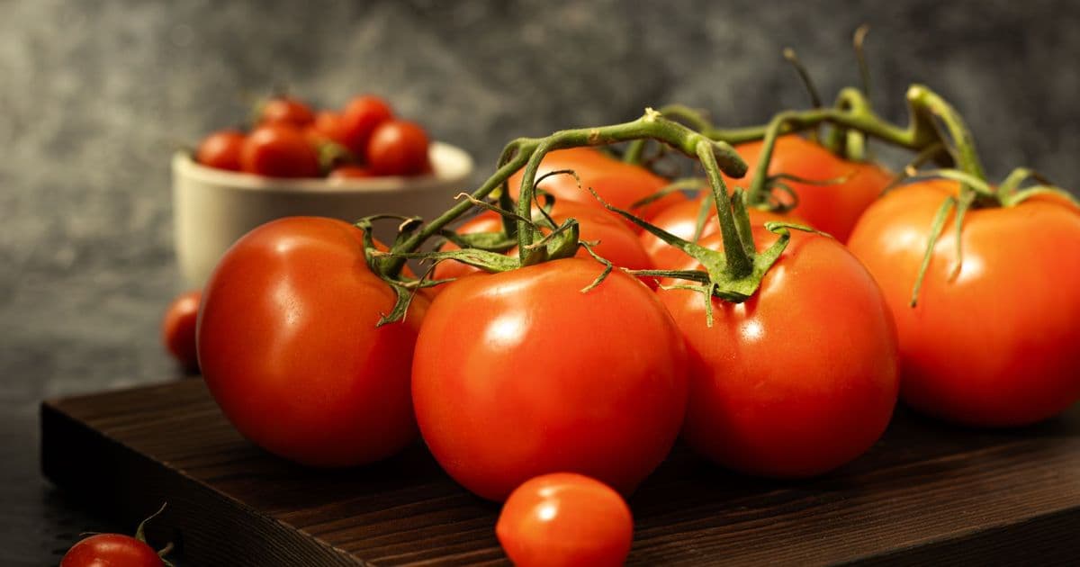 A close-up shot of fresh vine tomatoes on a rustic wooden board, showcasing their vibrant red color.