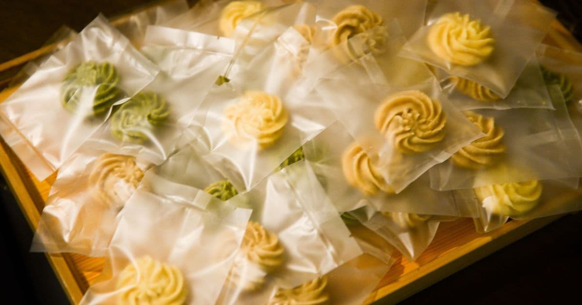 A collection of assorted cookies elegantly presented in transparent packaging on a wooden tray.