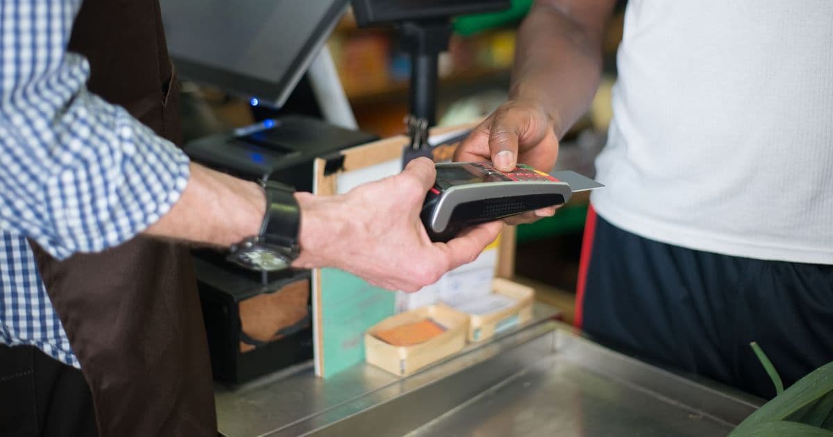 A customer making a payment with a credit card at a store checkout counter using a card reader.