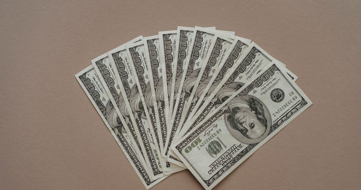 A neat arrangement of US dollar banknotes laid out in a fan shape on a brown surface.