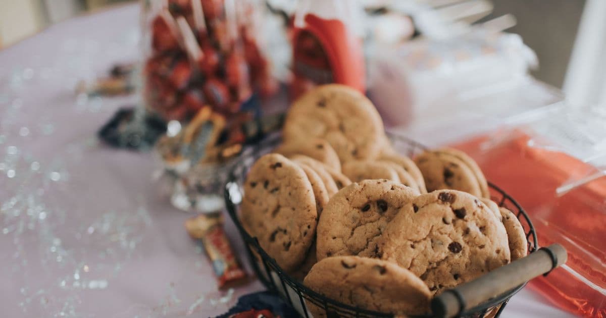 Basket of homemade chocolate chip cookies with candy on a festive table.